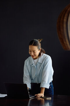 Happy Korean businesswoman working on laptop in office.