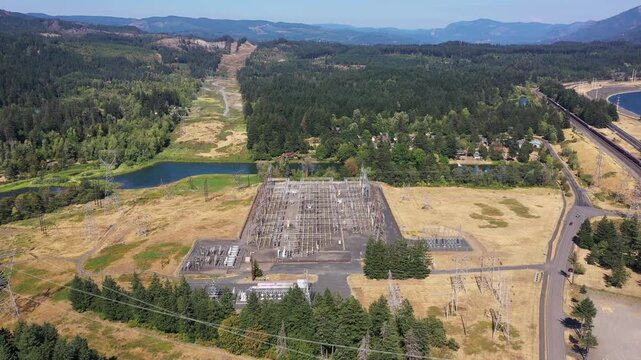 4K aerial drone footage of electrical substation near Bonneville Dam, Washington, USA, showing transformers, power lines and transmission infrastructure surrounded by Columbia Gorge landscape