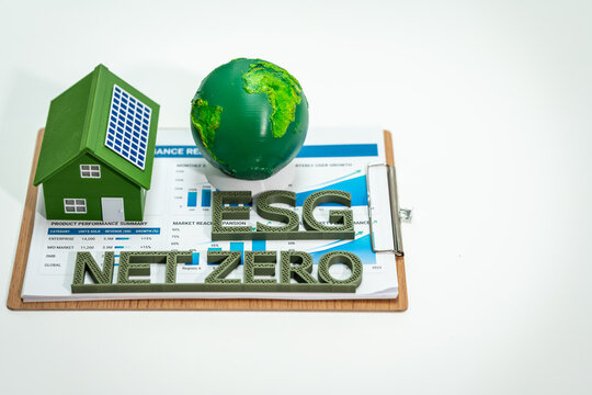 Green house model, globe and esg letters on a report clipboard, symbolizing net zero and sustainable finance.