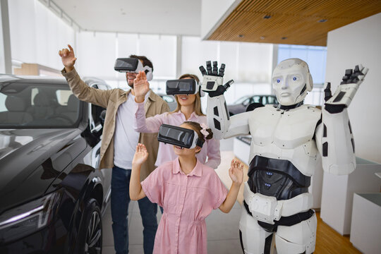 A family and a humanoid robot interact with virtual reality headsets in a modern car dealership environment