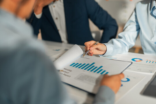 Business professionals collaborating, discussing monthly product sales reports with charts and graphs, planning strategy in a meeting