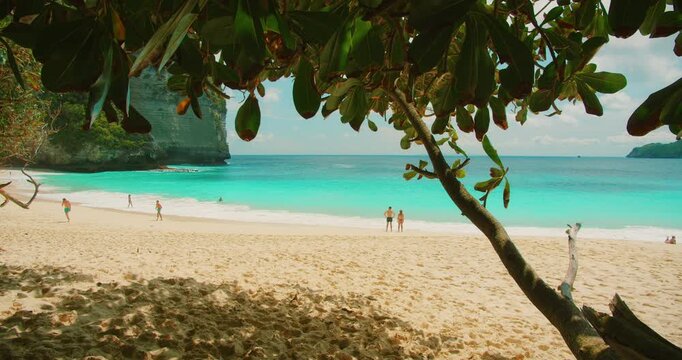 People relax on the pristine sandy shore of Kelingking Beach in Nusa Penida