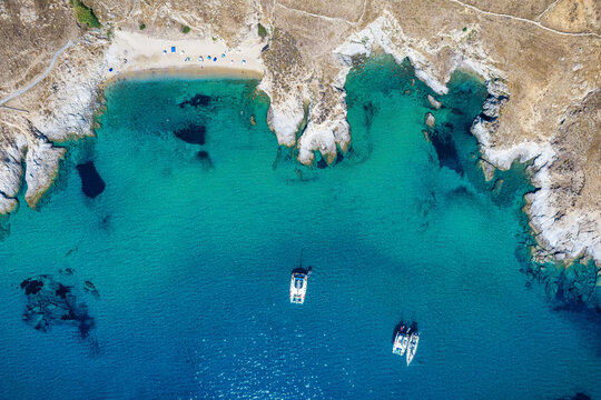 Aerial overhead view of the coast fo Serifos island, Cyclades, Greece, with Kalo Ampeli beach and moored sailboats over turquoise sea