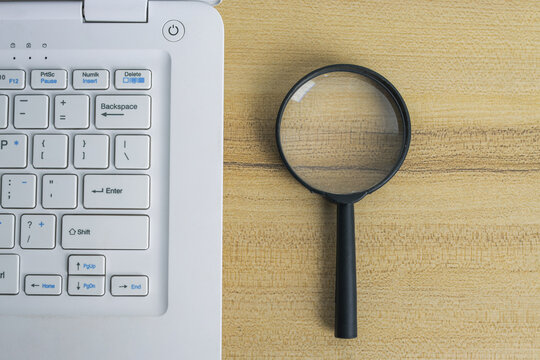 Top View of Magnifying Glass Placed Beside Laptop