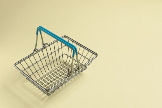 Small silver shopping basket on beige background, space for text