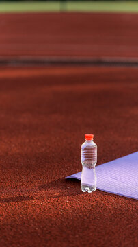 Hydration essential: water bottle rests on a yoga mat on a running track
