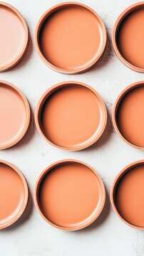 Round orange terracotta plates arranged in a precise uniform pattern on a light gray textured background. Clean simple minimalist design.