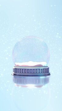 Empty transparent snow globe stands on a reflective surface while snow falls across a pale blue winter background. Perfect for Christmas greetings, product displays, festive titles and magical scenes.