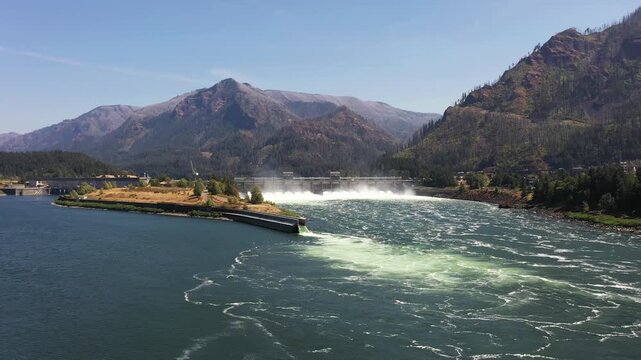 4K aerial drone footage of Bonneville Dam in Columbia River Gorge, Oregon, USA, releasing powerful water through spillways between Oregon & Washington, showcasing hydroelectric power, renewable energy