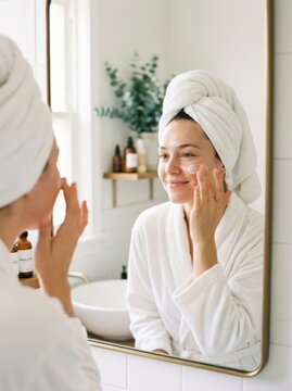 Woman applying face cream in a bright bathroom