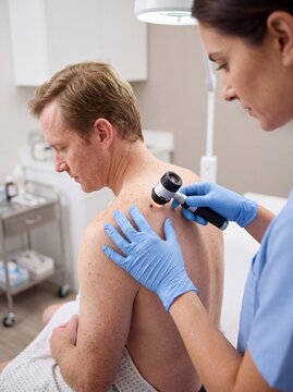 dermatologist skin examination man patient clinic dermoscopy back healthcare screening uses a dermoscope to examine a mans upper back and shoulder for dermatology branding and screening websites