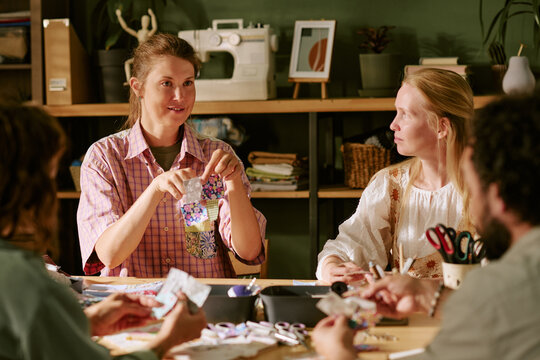 Diverse group of young adult Caucasian women and men participating in sewing workshop. Image suitable for promoting creative craft classes, local community workshops, or hobby education