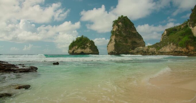 Turquoise waves roll onto a sandy tropical Diamond Beach in Nusa Penida
