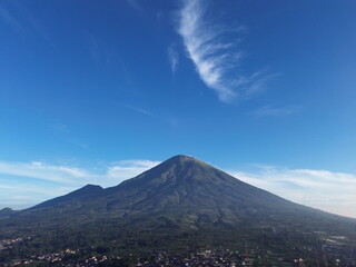 Fototapeta premium Aerial drone footage showcasing the majestic landscape of Mount Sumbing, an active stratovolcano and the second-highest volcano in Central Java, Indonesia.