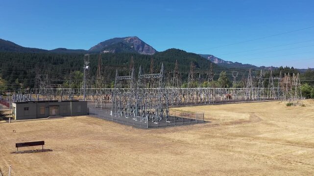 4K aerial drone footage of electrical substation near Bonneville Dam, Washington, USA, showing transformers, power lines and transmission infrastructure surrounded by Columbia Gorge landscape