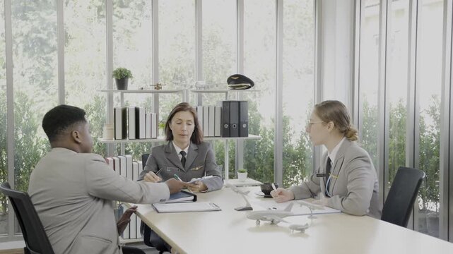 Airline team brainstorming and discussing strategy with sticky notes on a glass board during a workplace meeting