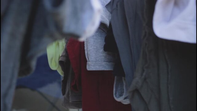 Gentle motion guides clothes as clothes are placed by hand into drying setup. Soft focus frames clothes with textile clarity. Concept of clothes expressing mindful interaction with home routine.