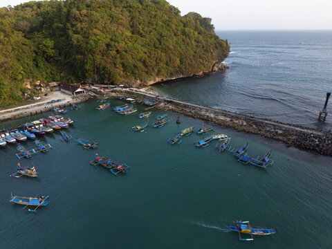 Aerial Drone View of Traditional Fishing Boats Moored at Sadeng Fishing Port During Sunset, Yogyakarta, Indonesia