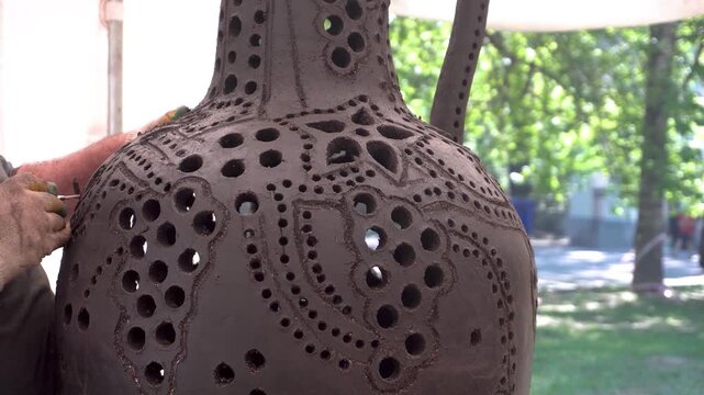 A potter is shaping a large clay vase, demonstrating ceramic artistry. The creation of a carved clay pitcher.