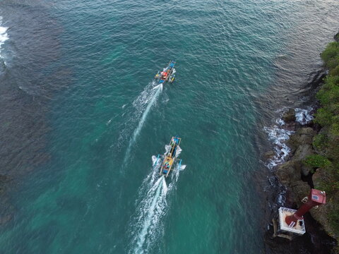 Aerial drone footage of a traditional fishing boat sailing across the vast open ocean. Cinematic aerial perspective capturing the vessel moving through deep blue waters with gentle waves