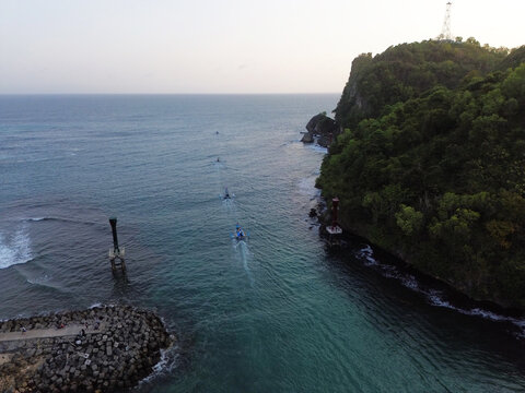 Aerial drone footage of a traditional fishing boat leaving the harbor pier and heading toward the open sea. Cinematic aerial perspective capturing the vessel departing from the dock