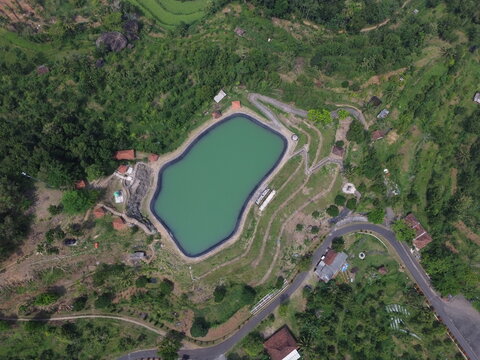Aerial drone footage of Embung Nglanggeran, a scenic artificial reservoir located in the Ancient Nglanggeran Volcano area, Yogyakarta, Indonesia.