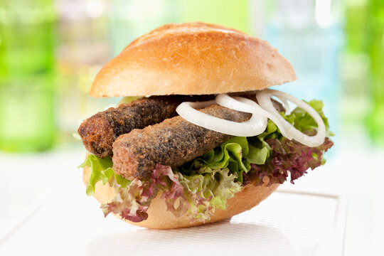Bread roll with fried herring and onions, close up