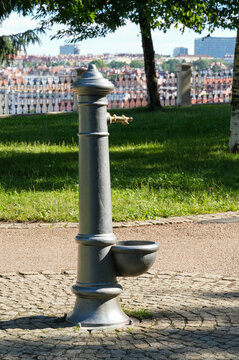 Vintage cast iron drinking water fountain in a public park with a city view.