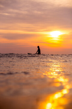 Indonesia, Bali, female surfer in the ocean at sunset