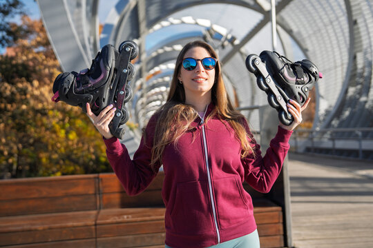 Woman holding inline skates smiling outdoors in madrid