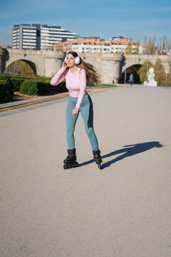 Woman rollerblading in urban park with headphones