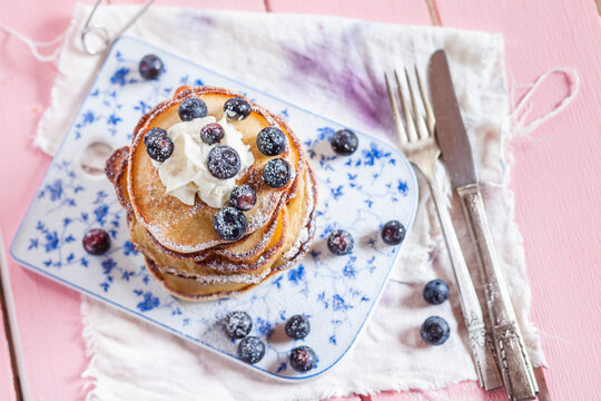 Stack of American pancakes with whipped cream and blueberries