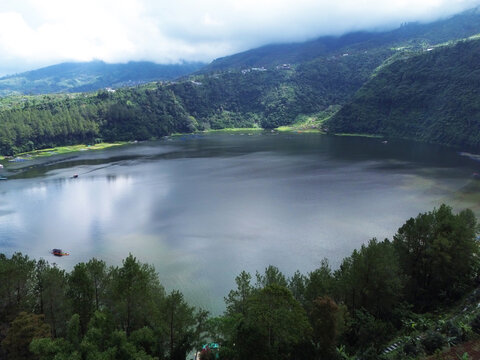 Aerial drone footage of Telaga Menjer, a beautiful volcanic lake located near the Dieng Plateau in Wonosobo, Central Java, Indonesia. Surrounded by lush green hills and spectacular mountain scenery