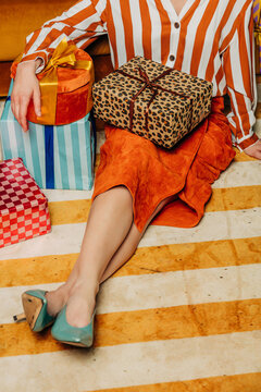 Stylish woman unwraps vintage holiday gift sitting on carpet
