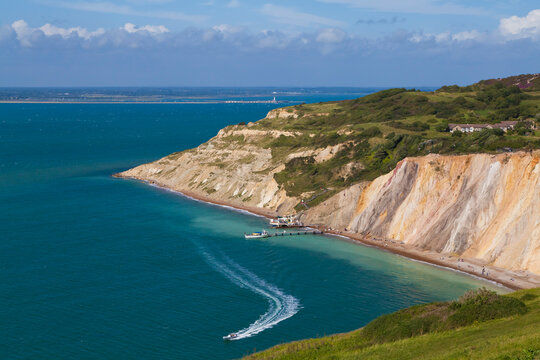 A boat sails past the chalk cliffs of Alum Bay on the Isle of Wight