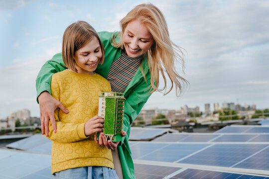 Mother and daughter hold an ecological house model outdoors