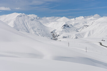 Fototapeta premium Aerial drone view of Gudauri ski resort in Georgia surrounded by snow covered Caucasus Mountains, with fresh white snow, pristine winter landscape and dramatic alpine scenery