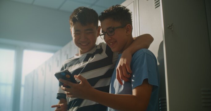 Close Friends Gather beside Personal Lockers, Looking at Content on Smartphone and Enjoying Lighthearted Moment Between Classes. Student Friendship, Digital Communication, Social Side of School Life.