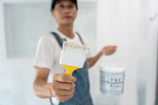 painter man show brush for products to restore and paint the wall, indoor the building site of a house, wall during painting, renovation, painting, contractor, Architect, construction worker