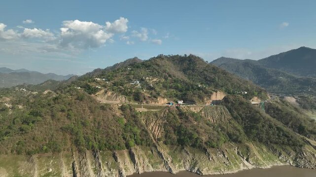 Aerial view of mountain highway passing through a green hillside village in Lahaul Valley Himachal Pradesh India shot by a drone
