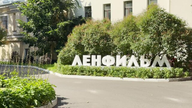 The Lenfilm sign stands proudly on a green lawn outside the famous film studio in Saint Petersburg. This bright scene evokes a warm feeling of creative inspiration and joyful nostalgia.