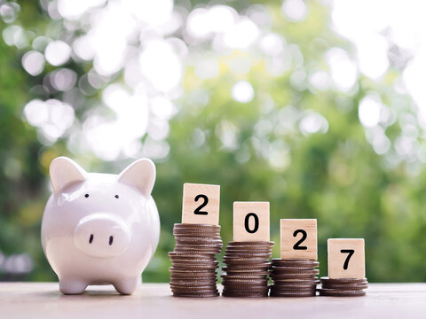 Pink piggy bank with stacked coins representing financial growth and savings on a wooden surface