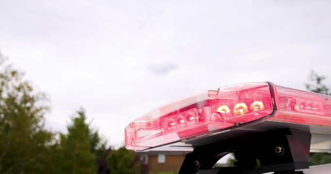 Close up footage of red flashing emergency lights on a British police car roof with a detailed view of the transparent LED light bar operating on an emergency response vehicle outdoors