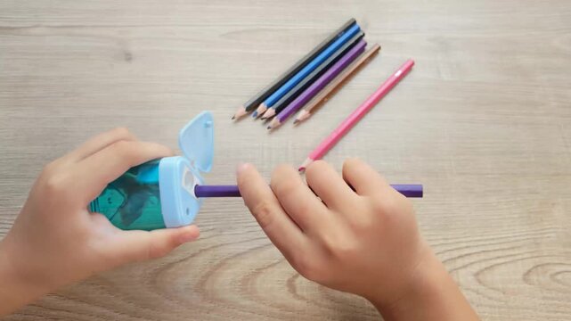 Child Hands Sharpening a Colored Pencil with a Pencil Sharpener