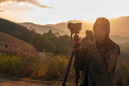 Silhouette of a happy photographer adjusting camera settings on a tripod
