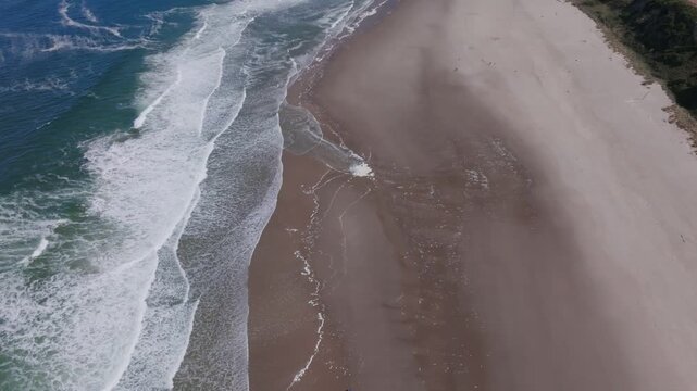 Aerial view of waves crashing on the sandy beach shoreline in Oregon City, Oregon, United States.