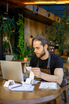 Entrepreneur managing cafe expenses with laptop