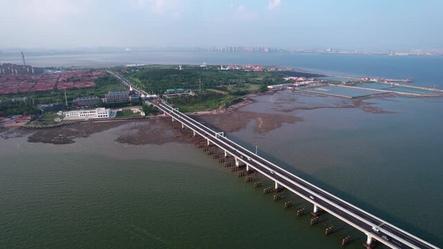 A coastal bridge spanning over tidal waters connecting coastal land areas under clear sky.