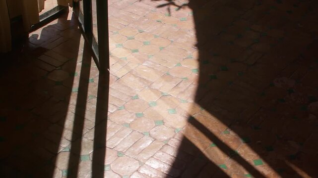Sunlight casts geometric shadows on patterned tile floor inside Marrakesh villa