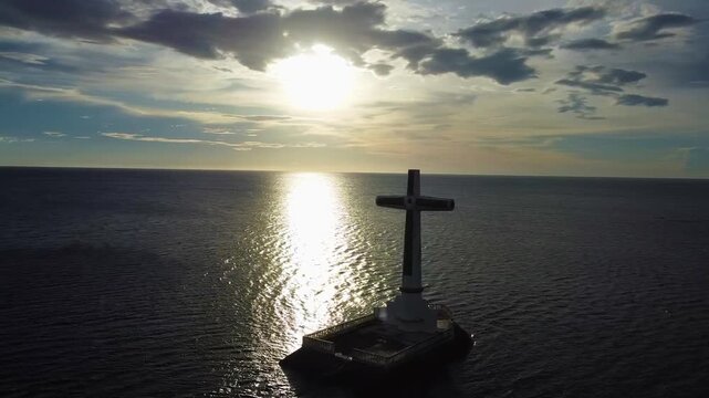 Aerial view of the Sunken Cemetery cross standing in the calm sea at sunset in Catarman, Camiguin, Philippines.